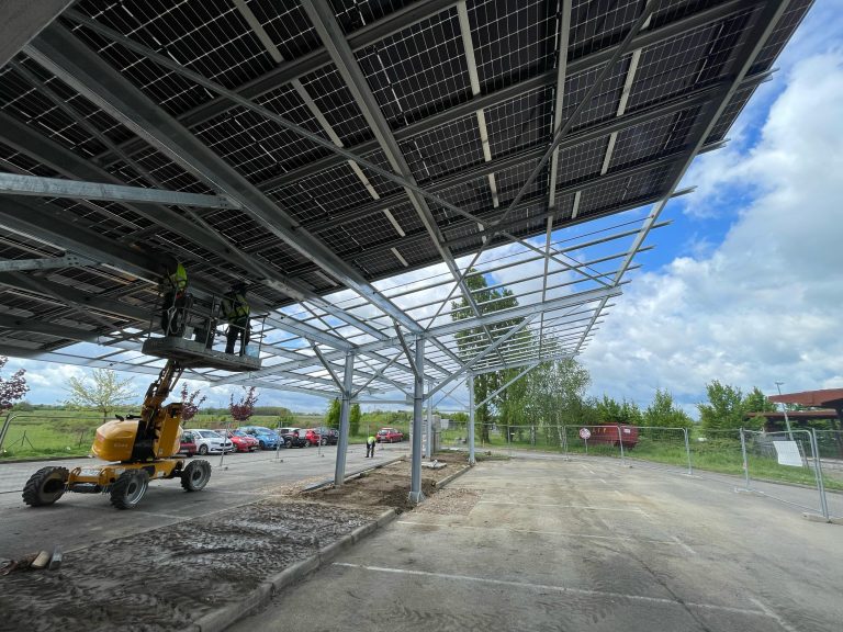 Avancement des travaux d'installation d'une ombrière sur le parking de la halte ferroviaire de St-Marcel-en-Dombes : pose de la quasi-totalité des 270 panneaux photovoltaïques de l'installation et réalisation des travaux électriques à venir